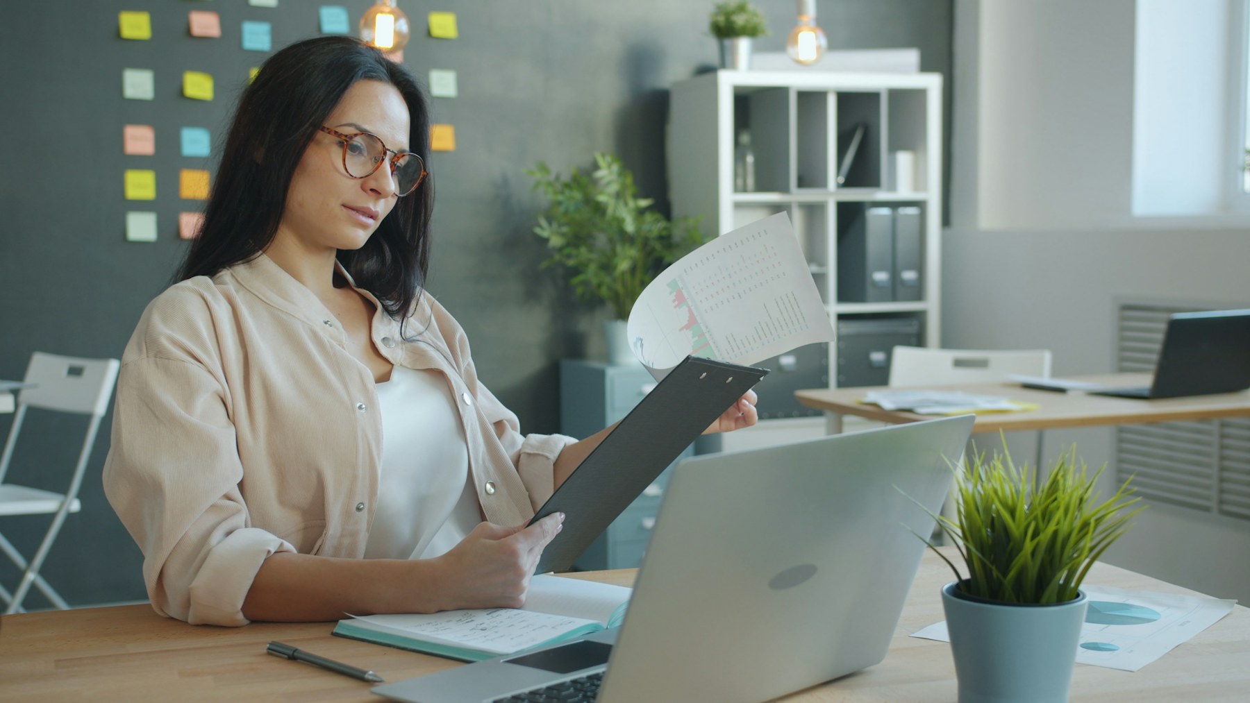 Bookkeeper reviewing financial documents beside a laptop