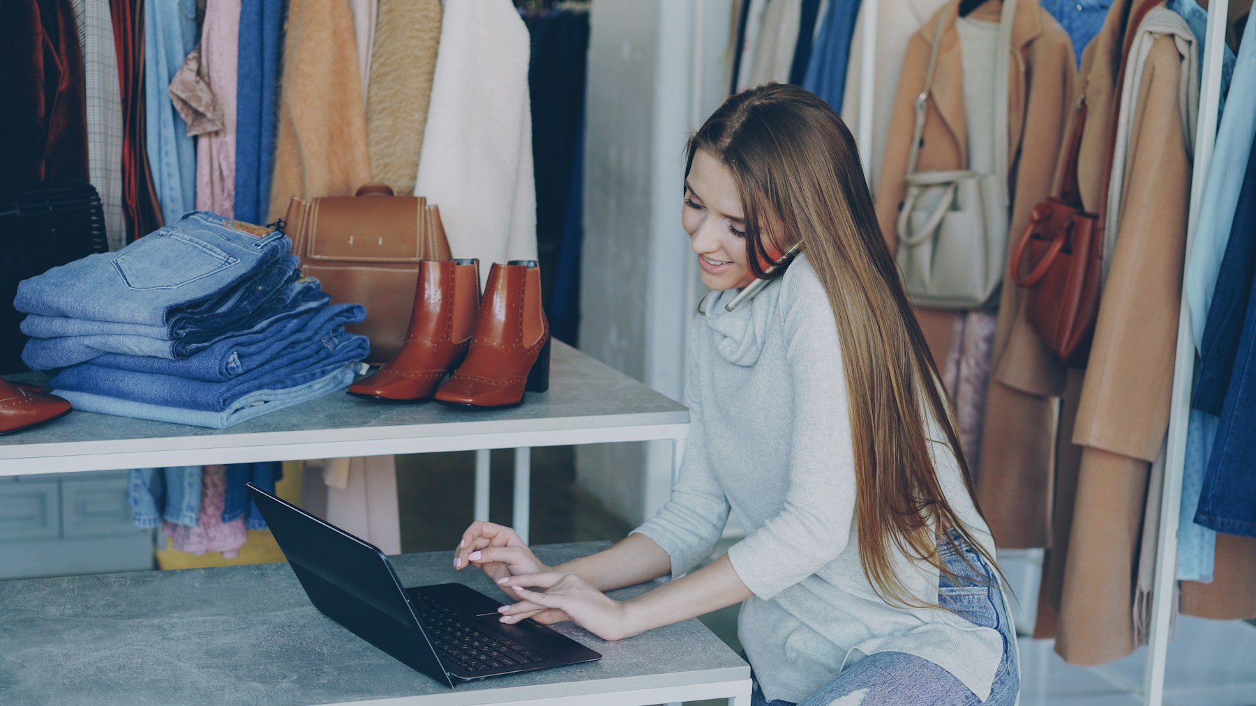 Retail business owner working on a laptop inside a clothing store